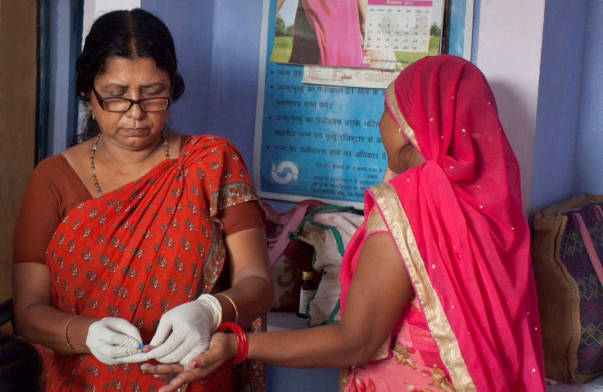 A trained health worker collecting a blood sample from a pregnant women for HIV testing. Plan India-Ahana Project.
