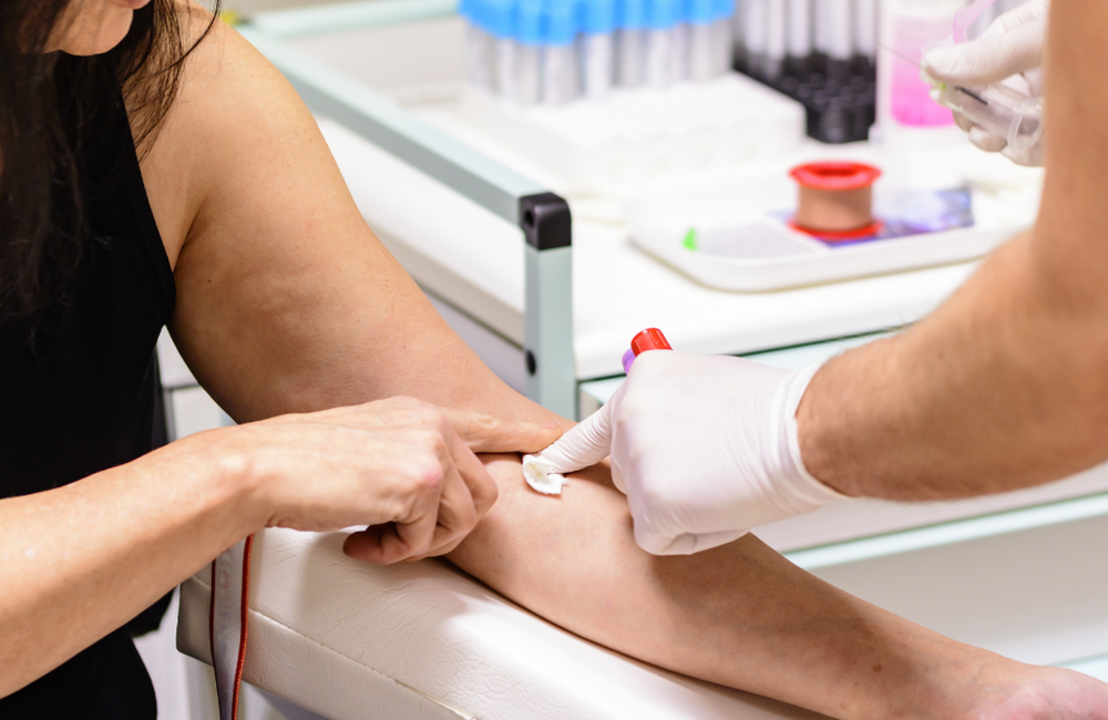 A person having a blood test. A nurse is holding some vials for the blood. 