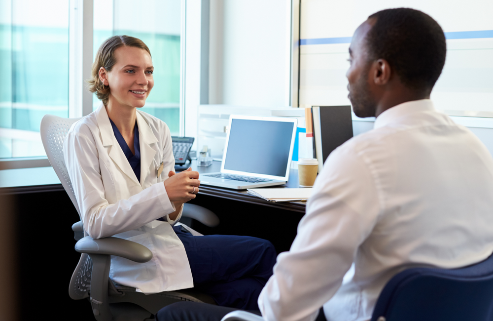 A doctor and patient talking in a doctor's office.