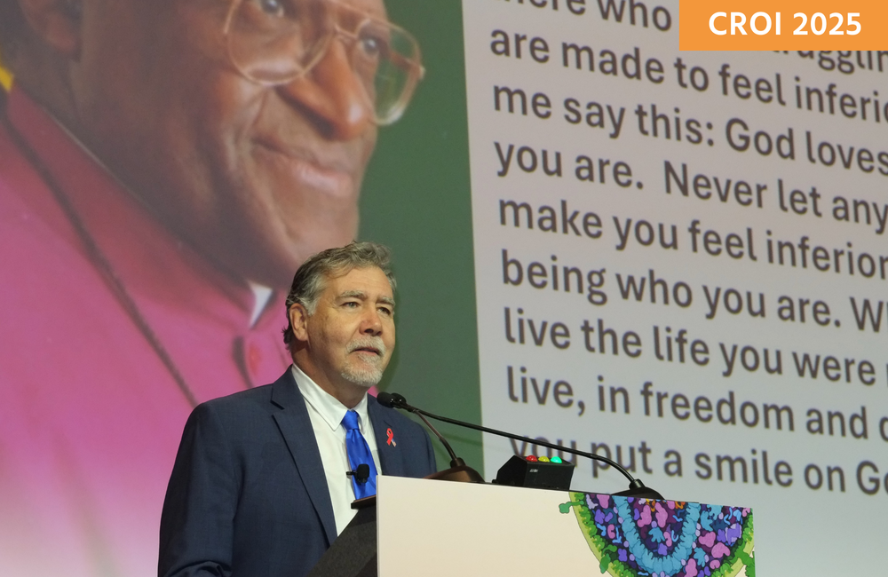 Professor Chris Beyrer presenting at CROI 2025. He is standing at a lectern in front of a screen.