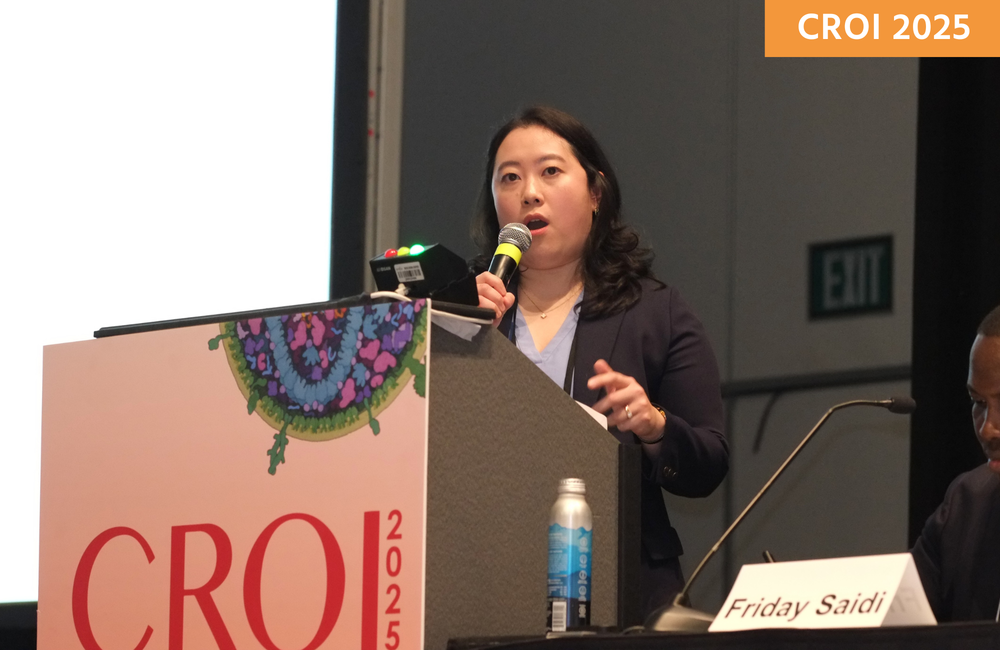 Michelle Yang at CROI 2025. She is standing at a lectern, talking into a microphone.