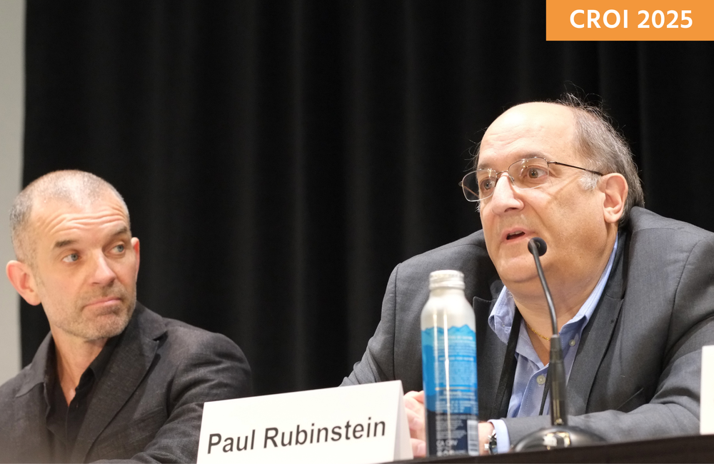 Two people at a media briefing at CROI 2025. Dr Paul Rubinstein (on the right) is talking into a microphone and Dr Marius Trøseid is next to him.