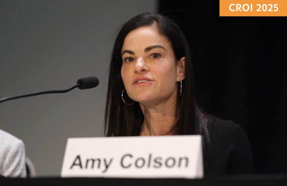 Dr Amy Colson speaking at a media briefing at CROI 2025. She is talking into a microphone.