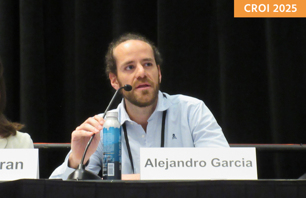 Dr Alejandro Garcia at a media briefing at CROI 2025. Alejandro is talking into a microphone.