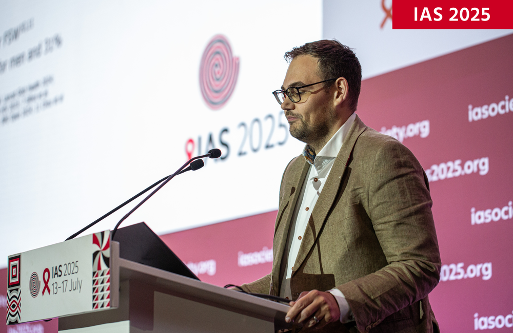Dr Jack Stone at IAS 2025. ©Jacques Nkinzingabo/IAS. CC BY-SA 4.0. Dr Jack Stone at IAS 2025. He is wearing a pale brown suit and has glasses. He's talking into a microphone behind a podium.
